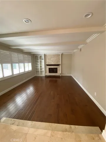 an empty room with wooden floor a fireplace and windows