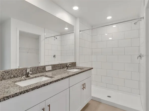 a bathroom with a granite countertop bathtub shower sink and vanity