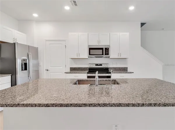 a kitchen with stainless steel appliances granite countertop a sink a stove and a refrigerator