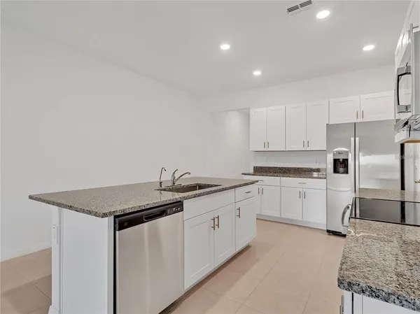 a kitchen that has a lot of white cabinets and stainless steel appliances