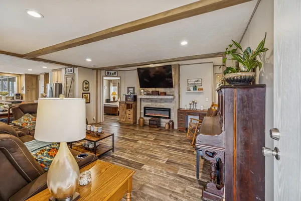 a living room with furniture a flat screen tv and a refrigerator