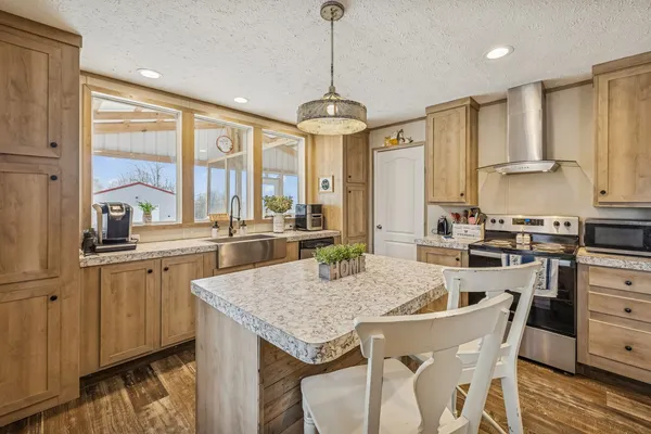 a kitchen with granite countertop a stove a sink a dining table and chairs