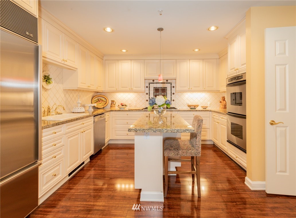 1331 Harbor Avenue Southwest, Unit 103 Seattle, WA 98116 - Photo 13 of 32 a kitchen with stainless steel appliances kitchen island granite countertop a sink and cabinets