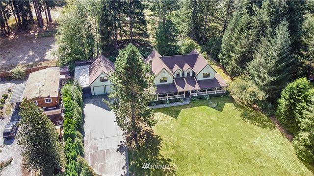 an aerial view of a house with swimming pool and large trees