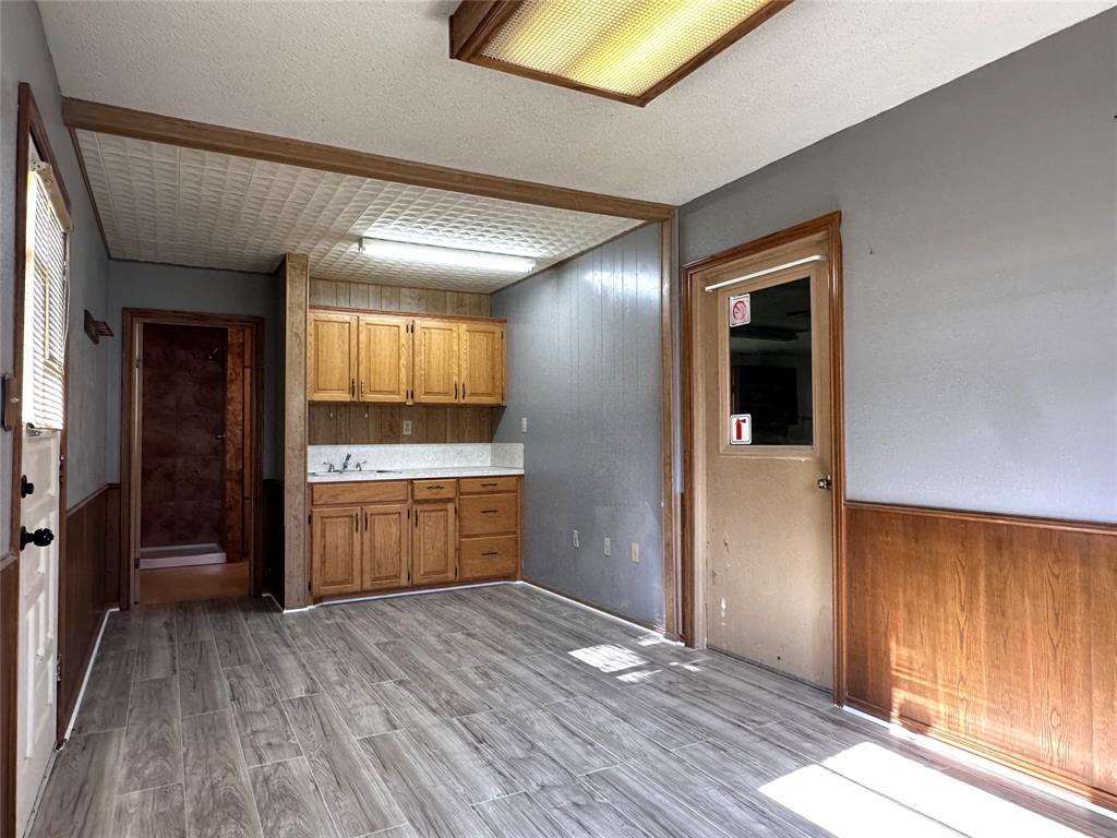 205 First Street Bangs, TX 76823 - Photo 4 of 16 wooden floor in an empty room with a kitchen
