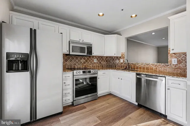 a kitchen with granite countertop white cabinets and stainless steel appliances