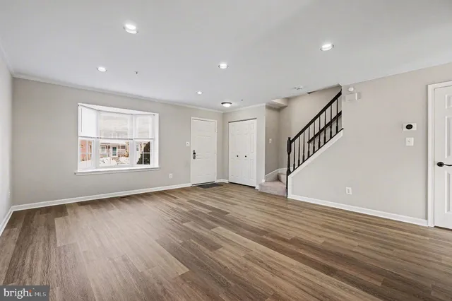 a view of an empty room with wooden floor and stairs