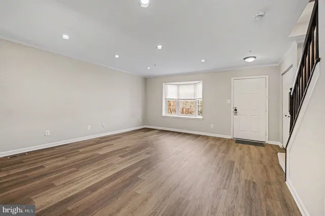 an empty room with wooden floor and window