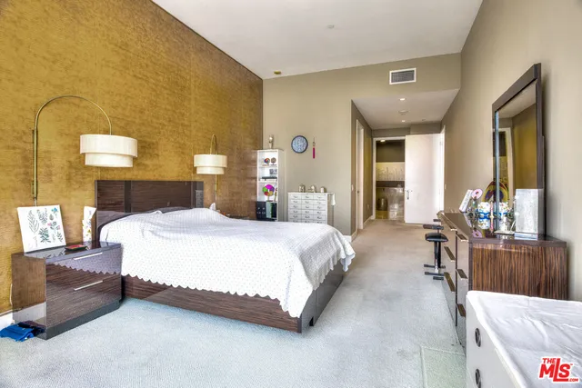 a spacious bedroom with a bed couch and a dresser next to a window