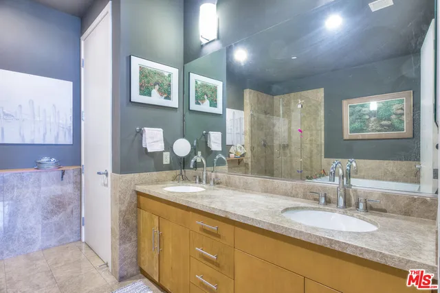 a bathroom with a granite countertop double vanity sink a mirror and a shower