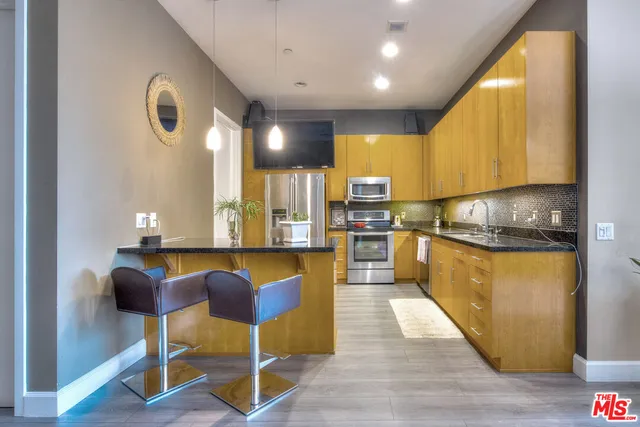 a kitchen with stainless steel appliances kitchen island granite countertop a table chairs in it and wooden floors
