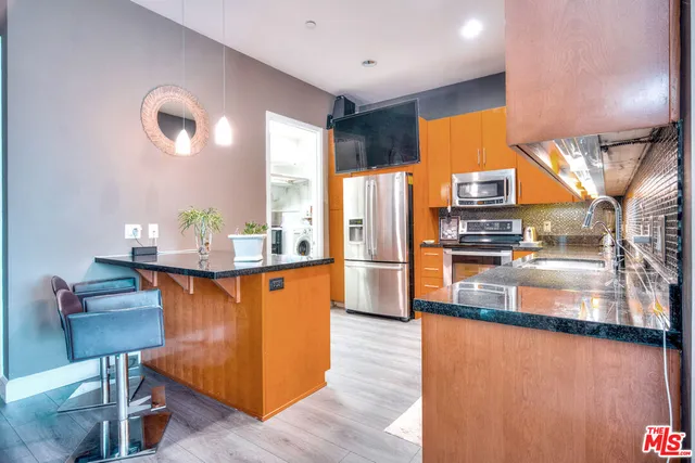 a kitchen with stainless steel appliances granite countertop a refrigerator a stove and a wooden floors