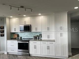 4650 Links Village Drive, Unit B503 Ponce Inlet, FL 32127 - Photo 16 of 47 a kitchen with kitchen island granite countertop white cabinets and stainless steel appliances
