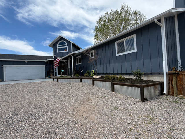 656 South Bullion Canyon Road Marysvale, UT 84750 - Photo 55 of 57 Board-and-batten siding with white trim, a large two-car garage, and a gravel driveway