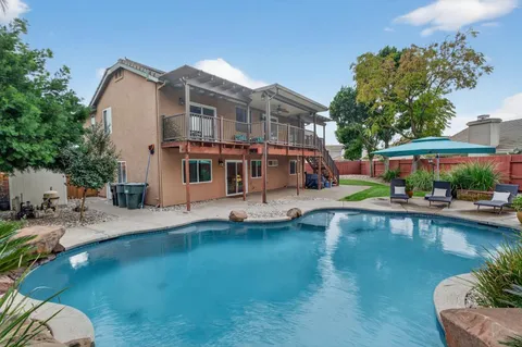 a view of pool with outdoor seating and house in the background