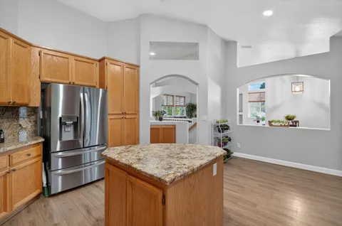 a kitchen with granite countertop a refrigerator and a stove top oven