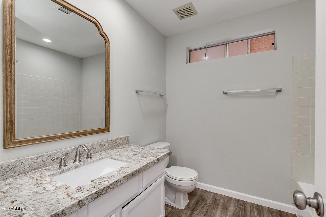 6149 Casper Road Mesa, AZ 85205 - Photo 11 of 21 a bathroom with a granite countertop sink a toilet and a mirror
