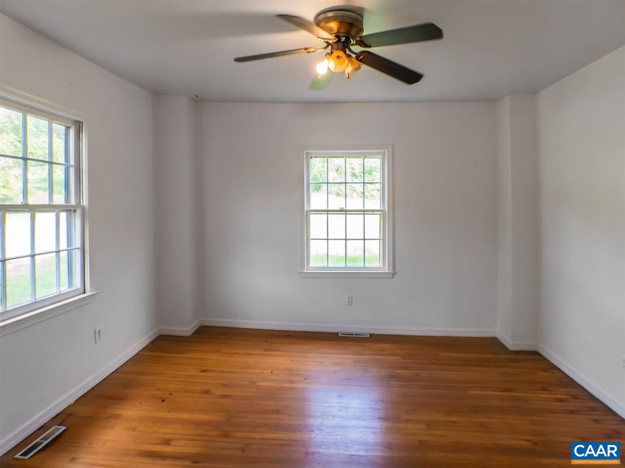 7595 Esmont Road Esmont, VA 22937 - Photo 11 of 30 an empty room with wooden floor fan and windows