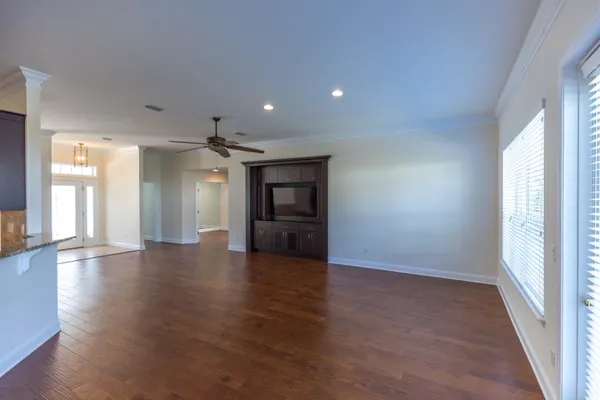 a view of an empty room with wooden floor and a window
