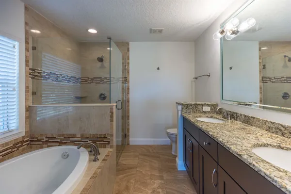 a bathroom with a granite countertop double vanity sink and a mirror