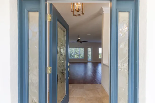 a view of a hallway with wooden floor windows and chandelier
