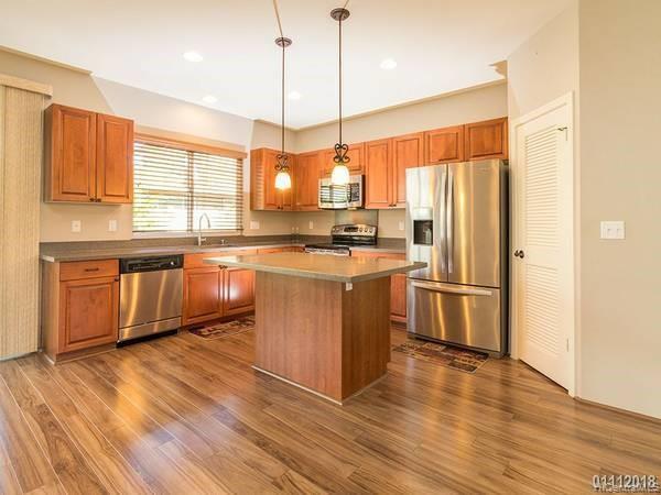 a kitchen with stainless steel appliances granite countertop a stove a sink dishwasher a refrigerator and white cabinets with wooden floor