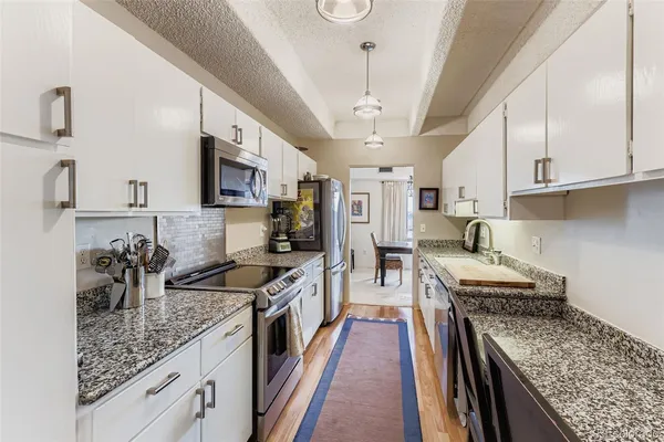 a kitchen with stainless steel appliances granite countertop a stove a sink dishwasher and cabinets with wooden floor