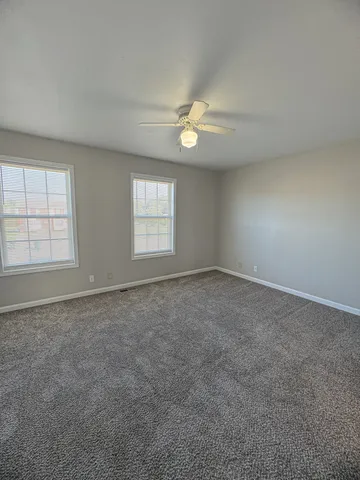 an empty room with windows and ceiling fan