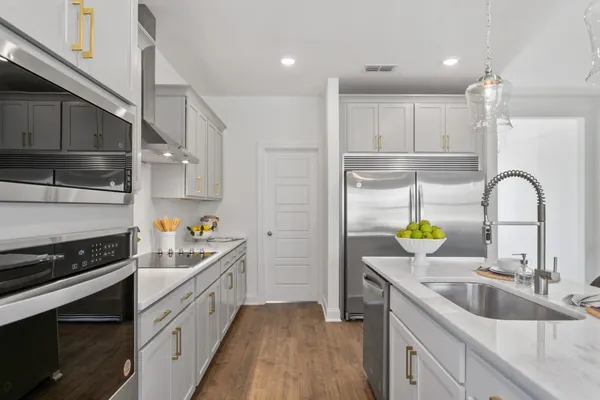 a kitchen with stainless steel appliances granite countertop a sink cabinets and wooden floor