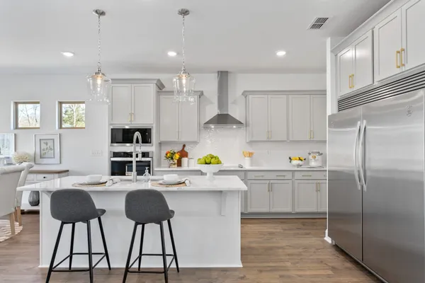 a kitchen with stainless steel appliances granite countertop a sink a stove a refrigerator cabinets and chairs