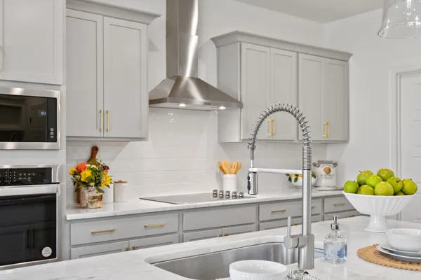 a kitchen with granite countertop a sink stainless steel appliances and white cabinets
