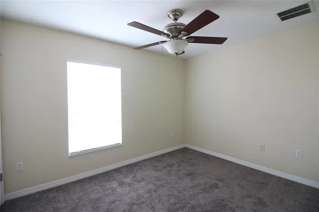an empty room with a window and a fan
