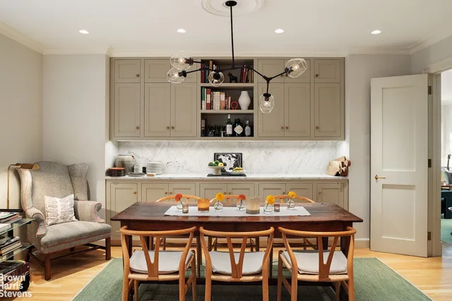 a view of a dining room and livingroom with furniture wooden floor a rug a fireplace and a chandelier