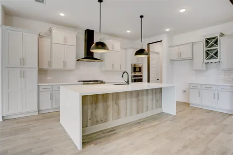 a kitchen with stainless steel appliances granite countertop a sink a stove a refrigerator and white cabinets