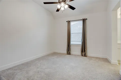 an empty room with a ceiling fan and carpet