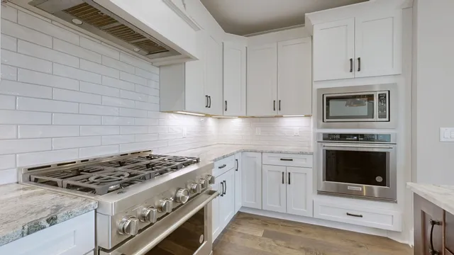 a kitchen with stainless steel appliances granite countertop a sink a stove and a window