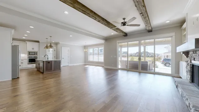 a view of an empty room with wooden floor and a kitchen