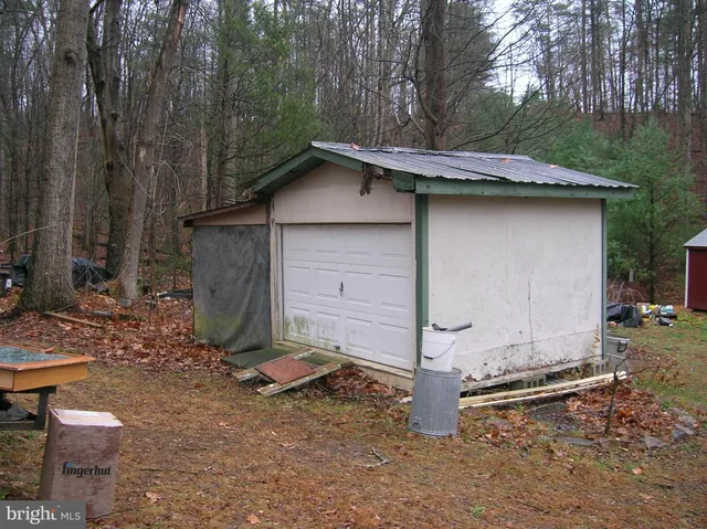 a small barn with a small yard and large trees