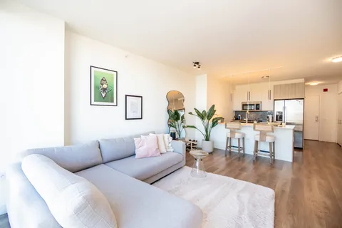 a living room with furniture kitchen view and a wooden floor