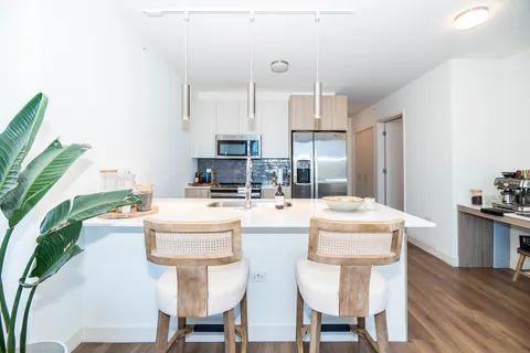 a kitchen with stainless steel appliances kitchen island granite countertop a table chairs and a refrigerator