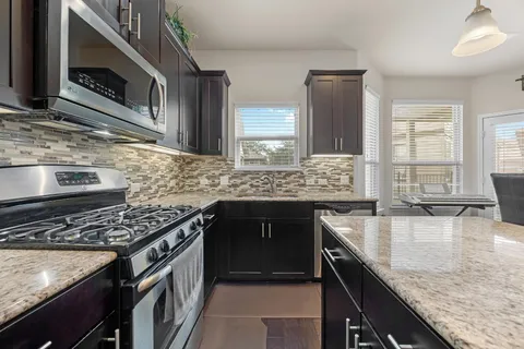 a kitchen with kitchen island a dining table chairs stainless steel appliances and cabinets