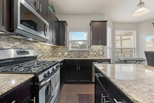 a kitchen with kitchen island a dining table chairs stainless steel appliances and cabinets