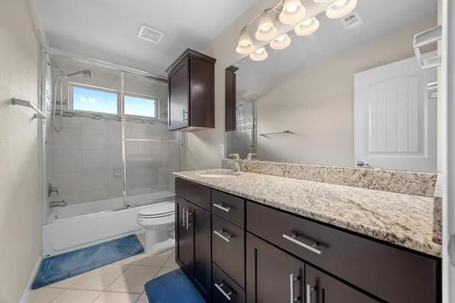 a bathroom with a granite countertop sink a mirror bathtub and shower
