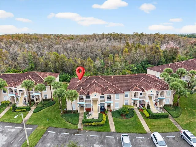 a view of a white house with a big yard plants and large trees