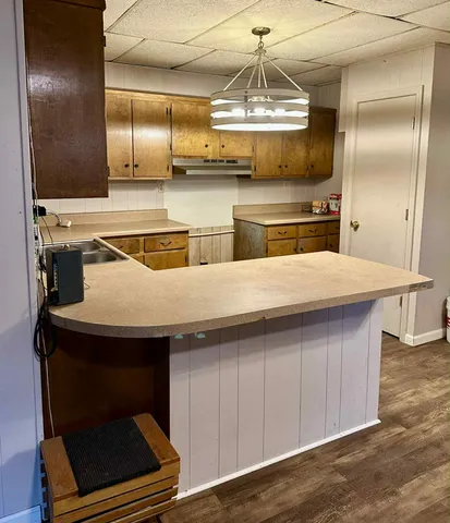 a kitchen with a sink stainless steel appliances and wooden floor