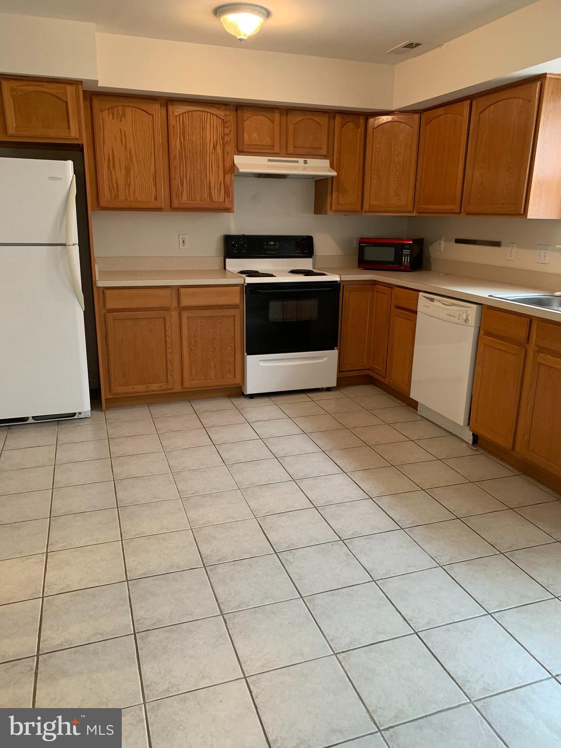 3916 6th Street, Unit B North Beach, MD 20714 - Photo 3 of 5 a kitchen with stainless steel appliances a sink a counter top space and cabinets