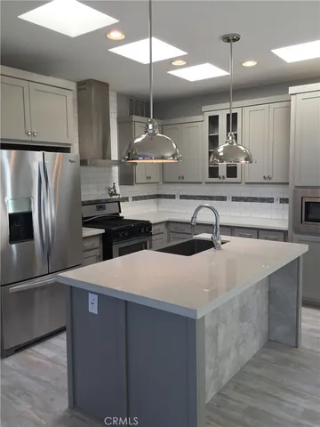 a kitchen with kitchen island a sink stainless steel appliances and refrigerator