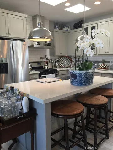 a kitchen with stainless steel appliances granite countertop a table chairs stove and refrigerator