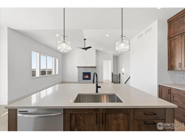 a kitchen with a sink a chandelier stainless steel appliances and cabinets