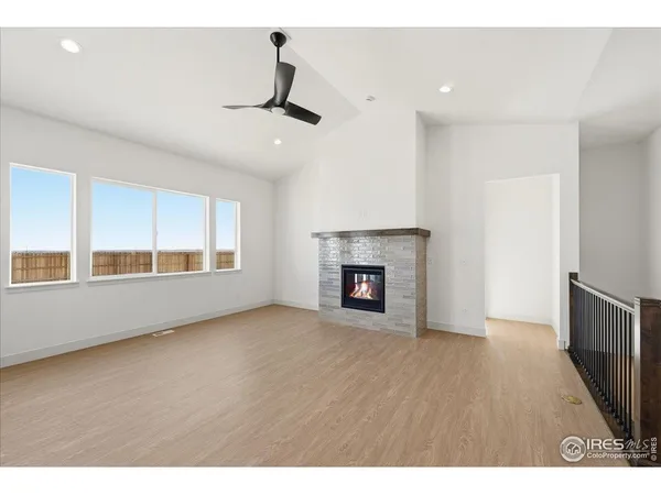 a view of an empty room with wooden floor fireplace and a window